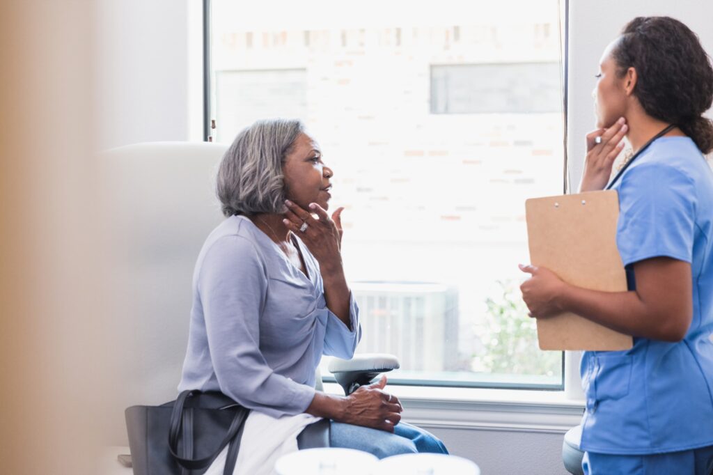 older patient showing nurse a mark on her face
